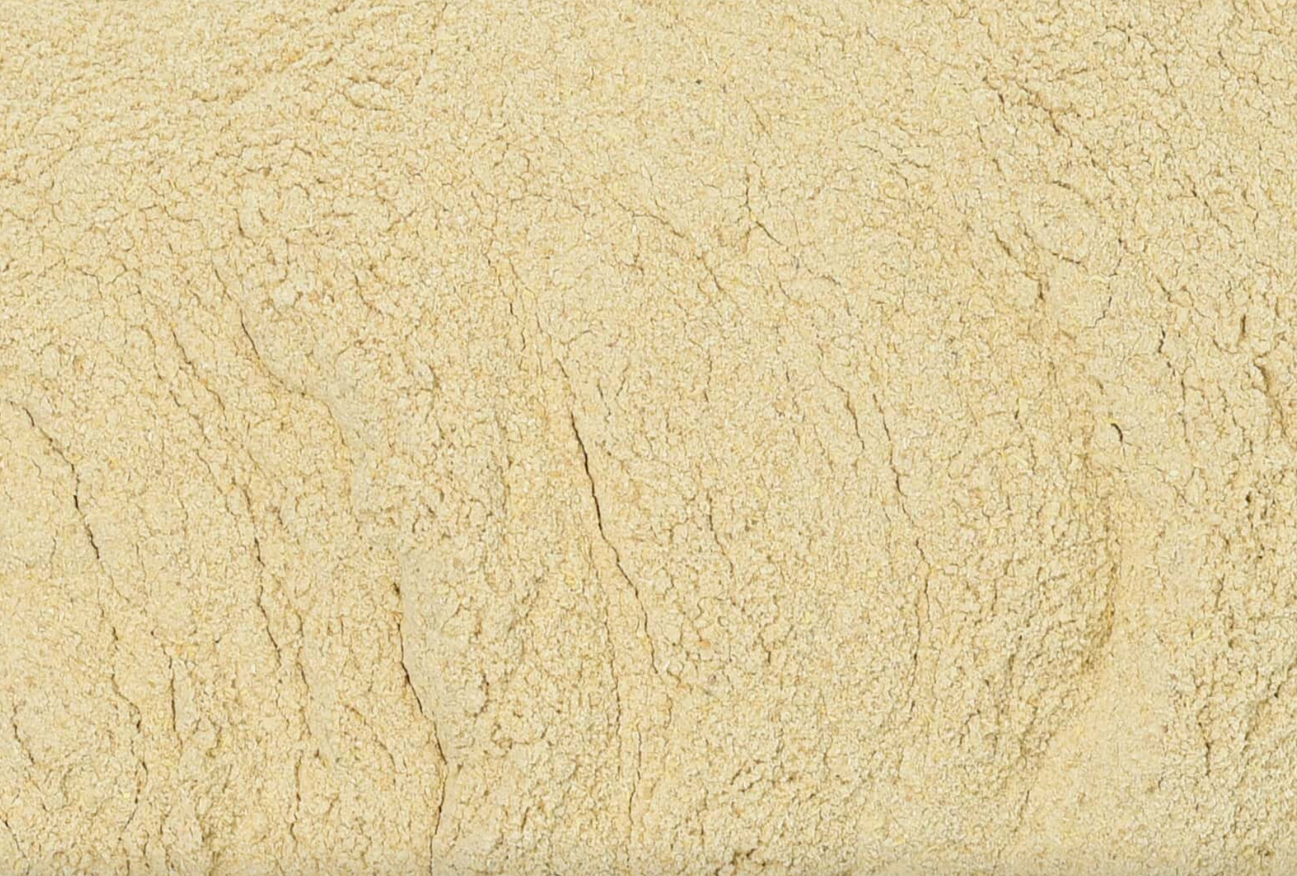 Close-up texture of dried ashwagandha root powder, showing fine beige powder used for teas and herbal remedies.