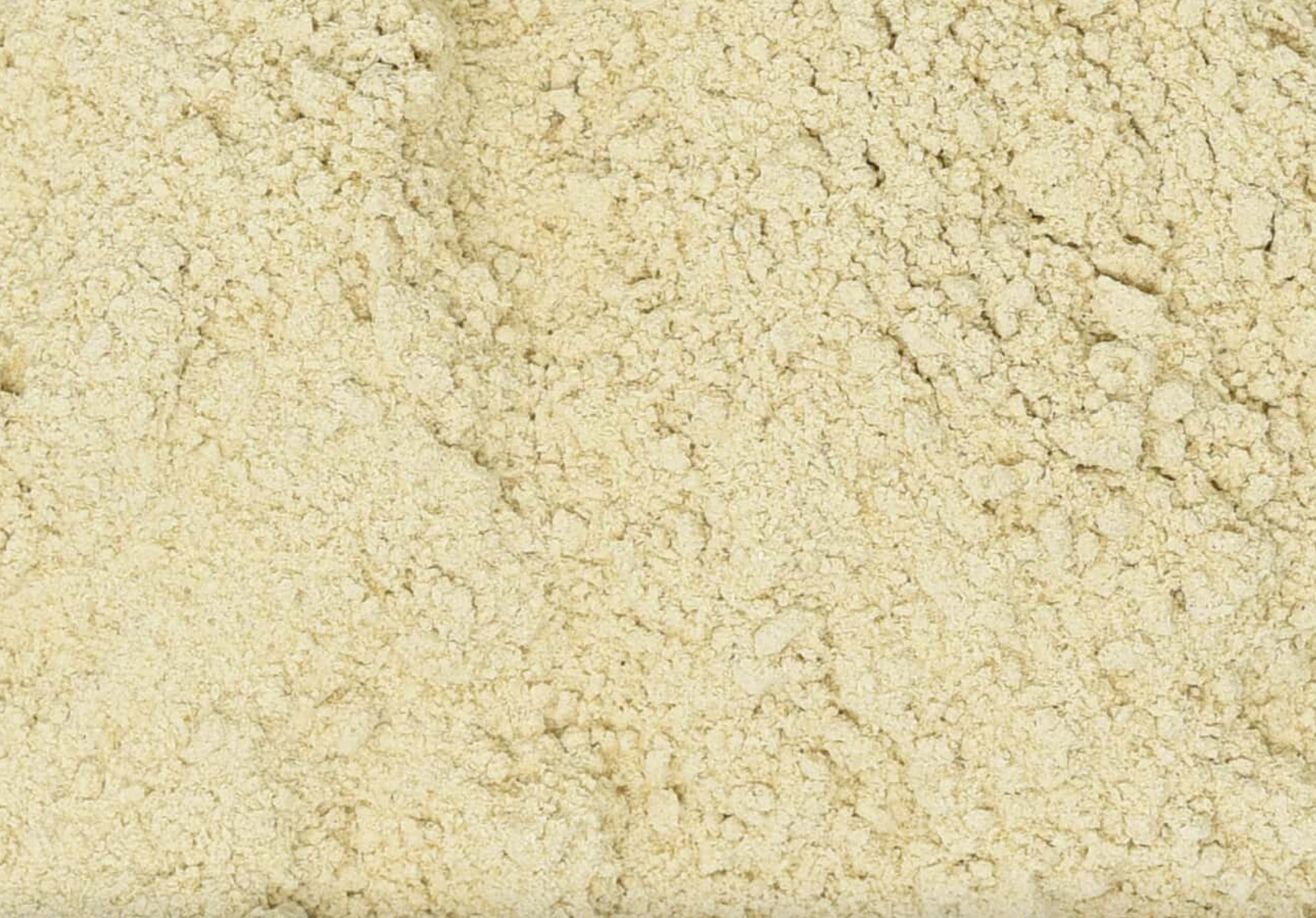 Close-up texture of dried astragalus root powder, showing fine beige powder used for teas and herbal remedies.
