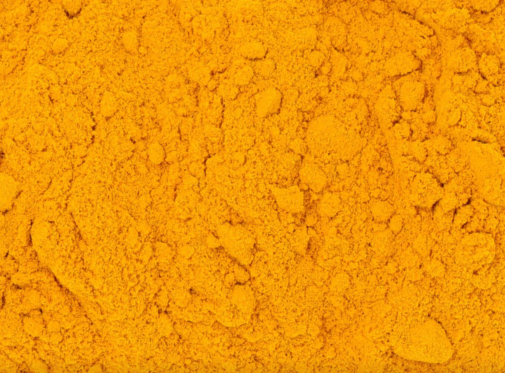 Close-up of dried turmeric root powder, showing vivid orange powder used for teas and herbal remedies.